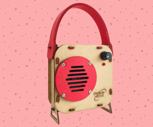Small wooden radio-like device with a red face on a pink background